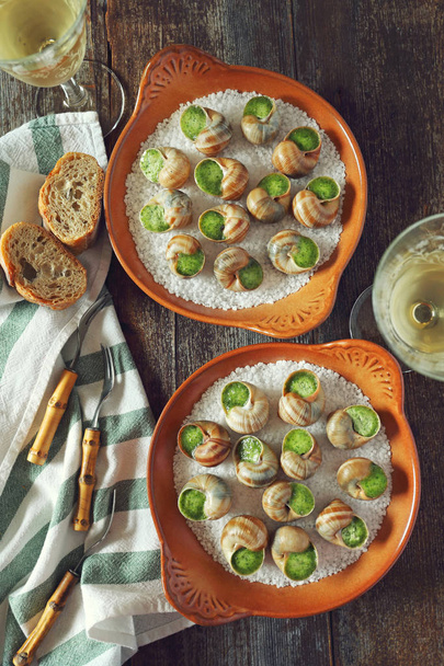 Escargots, cocina tradicional francesa: salsa de caracoles Borgoña y una copa de vino blanco. Vista superior, imagen tonificada
 - Foto, imagen