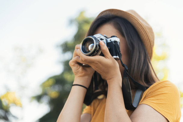 Young woman using a camera to take photo at the park. - Foto, Imagen