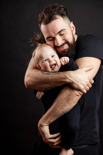 Young athletic father with adorable baby on black background - Valokuva, kuva