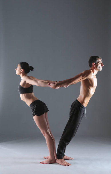 Young couple practicing acro yoga on mat in studio together. Acroyoga. Couple yoga. Partner yoga. - Fotografie, Obrázek