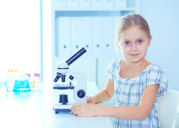 Schoolgirl looking through microscope in science class. - 写真・画像