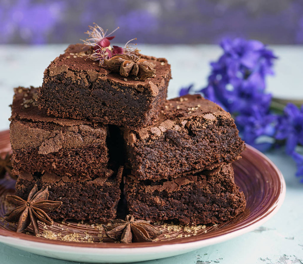 hromada čtvercové pečené kusy čokoládové Brownie dort na hnědý keramický talíř, zblízka - Fotografie, Obrázek