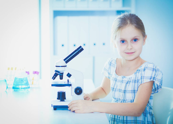 Schoolgirl looking through microscope in science class. - Zdjęcie, obraz