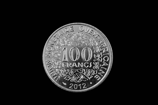 Uma imagem de perto de uma moeda de prata de 100 francos da África Ocidental isolada sobre um fundo preto
 - Foto, Imagem
