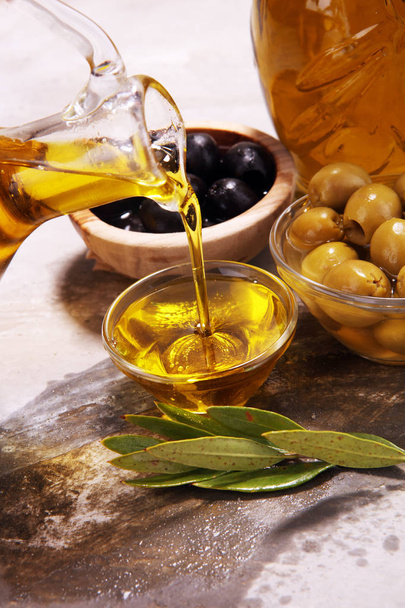 Botella de aceite de oliva virgen y aceite en un bol con algunas aceitunas
. - Foto, imagen