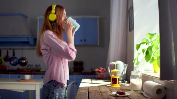 Morning at home, girl dancing in headphones and drinking tea. - Video