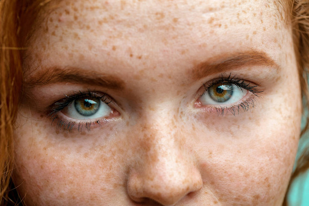 Close up macro face of young red ginger freckled woman with beautiful green eyes - Fotó, kép