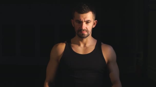 strong muscular bearded bodybuilder clapping hands with chalk powder before training with a dumbbell - Materiał filmowy, wideo