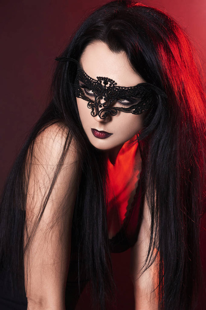 beautiful girl on halloween in mask.young woman in mask red colored spotlights portrait - Foto, Imagem