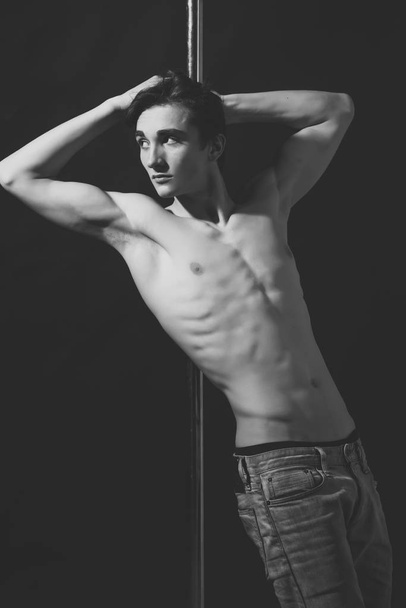 thin, taut man. Young strong pole dance man with torso lean on pole. - Foto, Imagem
