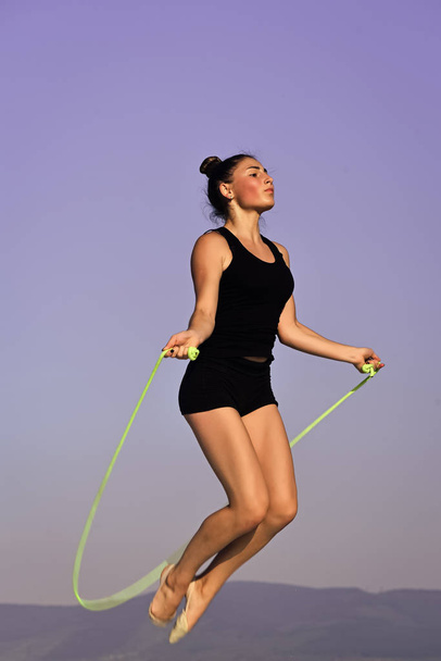 exercises with a skipping rope. Workout of girl on blue sky background. - Zdjęcie, obraz