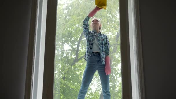 ludzie, prace domowe i sprzątanie koncepcja - szczęśliwa kobieta w rękawice do czyszczenia okien z szmata i mycia spray w domu - Materiał filmowy, wideo