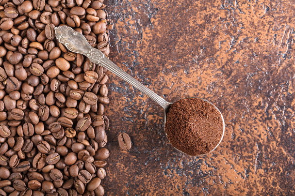 Black roasted coffee grains and ground coffee in spoon lie on a copper table, background image, top view, copy space for your text. - Photo, Image