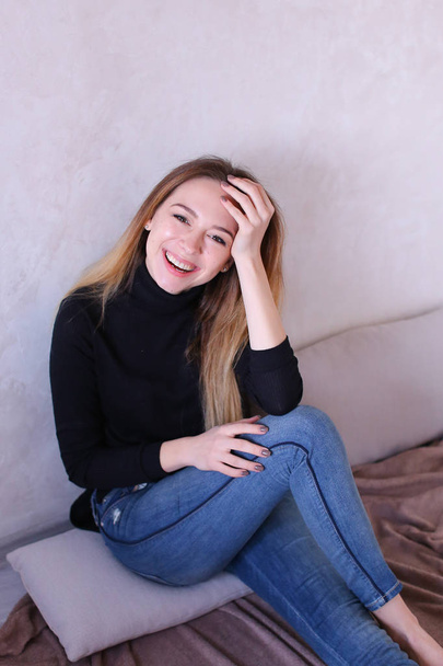 Young charming girl wearing black blouse sitting near wall. - Фото, изображение