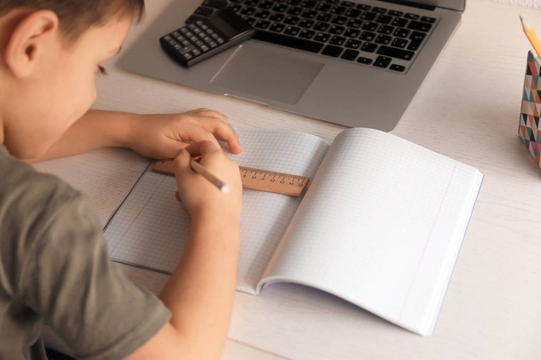 Милий маленький хлопчик робить домашнє завдання в приміщенні
 - Фото, зображення