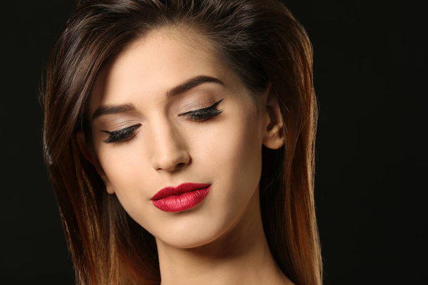 Attractive young woman with elegant makeup and long eyelashes on black background. Eyelash extensions - Photo, image
