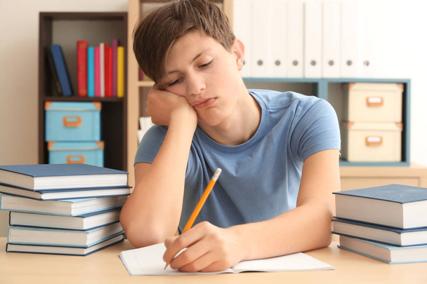 Tired teenager boy doing homework in library - Zdjęcie, obraz