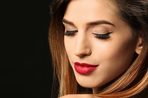 Attractive young woman with elegant makeup and long eyelashes on black background. Eyelash extensions - Valokuva, kuva