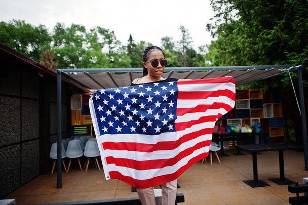 Stylish african american woman in sunglasses posed outdoor with usa flag. - 写真・画像