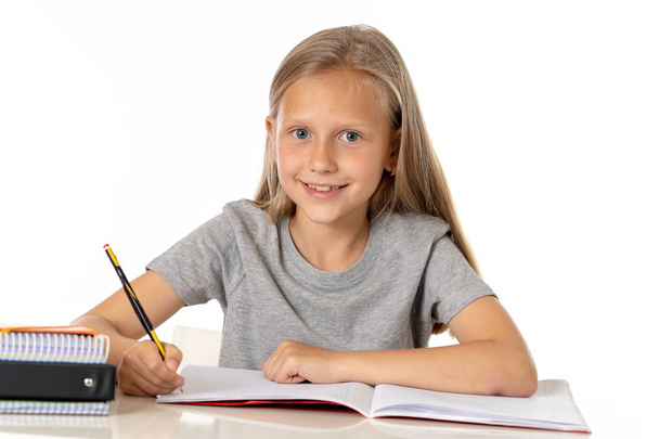 Η εκπαίδευση με την αρχική έννοια. χαριτωμένο νεαρή ξανθιά Καυκάσιος κοριτσάκι μελέτη ή να κάνει εργασία στο σπίτι στο τραπέζι με το σωρό των βιβλίων, εκπαιδευτικά μελετώντας έννοια σε λευκό φόντο - Φωτογραφία, εικόνα