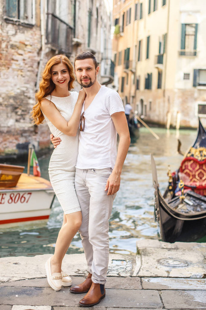 Young man embracing his girlfriend the quay of canal in Venice - 写真・画像