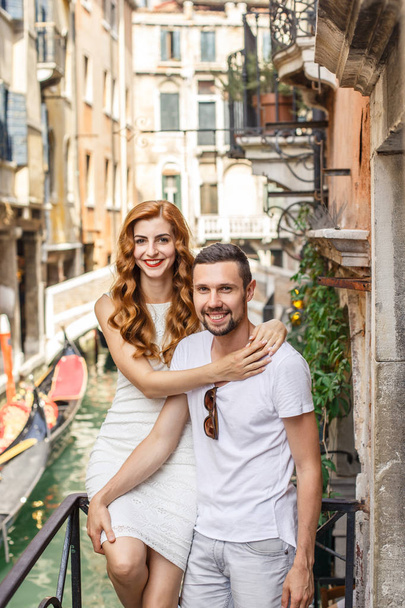 Young couple posing on balcony over the canal with bridge and gondola - 写真・画像