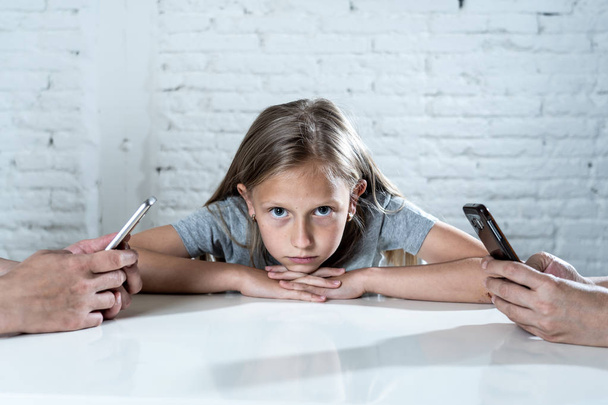 mother and father using mobile phones neglecting little sad ignored daughter bored and lonely feeling abandoned and disappointed with  parents.  mobile cell smart phone addiction bad behavior concept - Фото, изображение