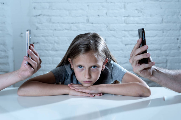 mother and father using mobile phones neglecting little sad ignored daughter bored and lonely feeling abandoned and disappointed with  parents.  mobile cell smart phone addiction bad behavior concept - Fotografie, Obrázek