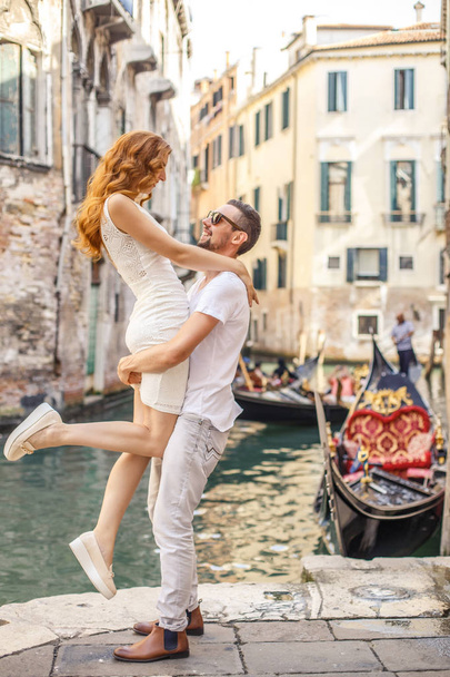 Young man raises his girlfriend up above the quay of canal in Venice - Фото, зображення