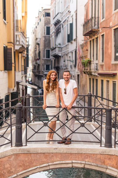 Young couple standing on bridge over the narrow canal in Venice - Zdjęcie, obraz