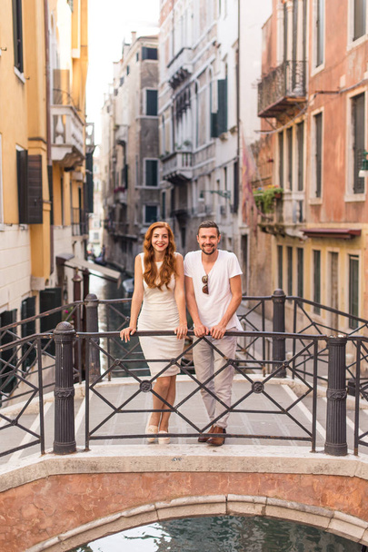 Young couple standing on bridge over the narrow canal in Venice - Foto, afbeelding