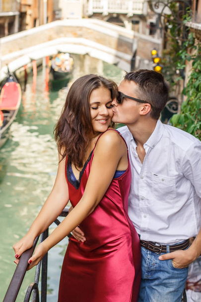 Young couple posing on balcony over the canal with bridge and gondola - Foto, imagen