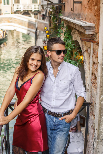 Young couple posing on balcony over the canal with bridge and gondola - Fotoğraf, Görsel