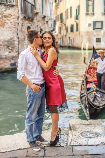 Young man embracing his girlfriend on quay of canal in Venice - Фото, зображення