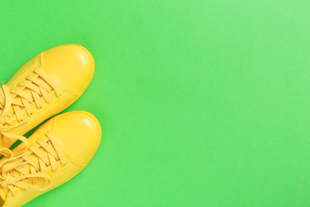 Pair of yellow shoes on green background. - Photo, Image