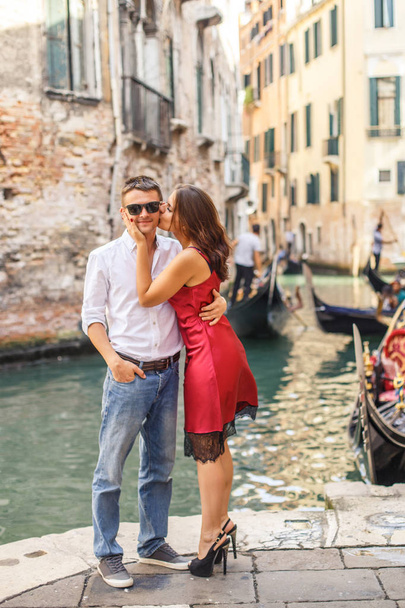 Young man embracing his girlfriend on quay of canal in Venice - Photo, image