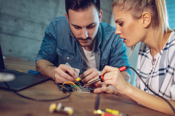 Dois jovens parceiros de negócios técnicos focados na reparação de equipamentos eletrônicos
 - Foto, Imagem