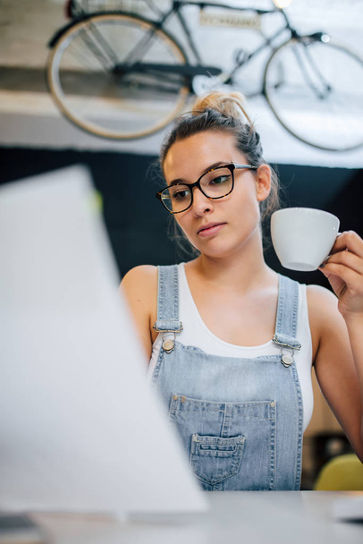 Immagine ravvicinata di una donna hipster millenaria che tiene una tazza al chiuso
. - Foto, immagini