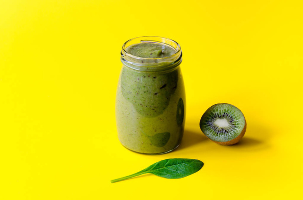 Green smoothie with kiwi and leaf of spinach on yellow background. Diet or Vegetarian concept. - Fotografie, Obrázek