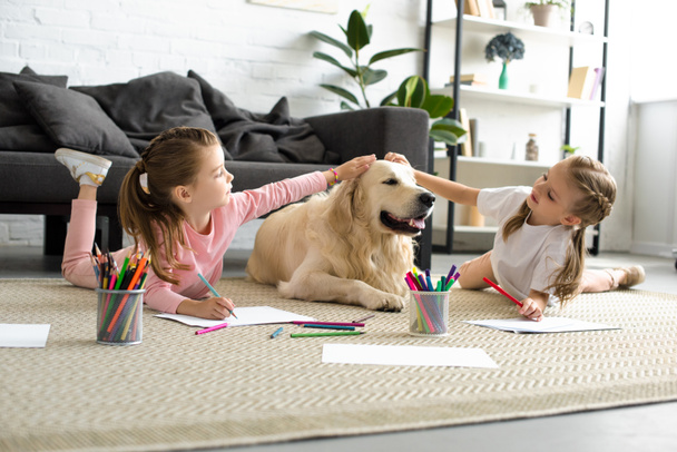 adorable kids petting golden retriever dog while drawing pictures on floor at home - Photo, Image