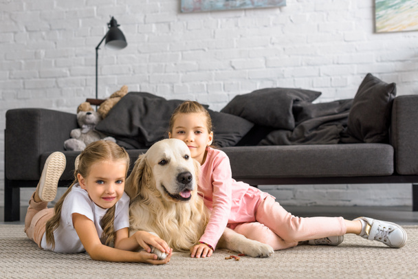 adorable kids hugging golden retriever dog while sitting on floor at home - Photo, Image