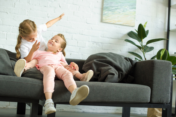 adorable little children having fun on sofa at home - Photo, Image