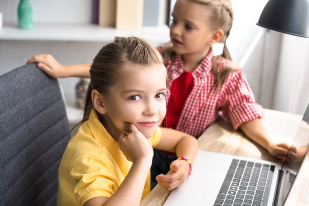 enfoque selectivo de los niños pequeños en la mesa con el ordenador portátil en casa
 - Foto, imagen