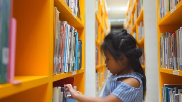 Schattig Aziatische little Girl lezen van boeken in School Class Library, - Video