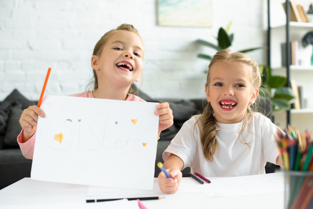 portrait of cheerful kids with drawing at table with pencils at home - Фото, зображення