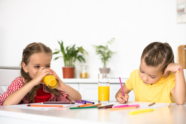 lindos niños pequeños dibujando imágenes en la mesa en casa
 - Foto, imagen