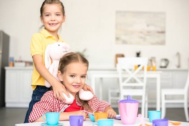 little smiling sisters pretending to have tea party together at home - Fotografie, Obrázek
