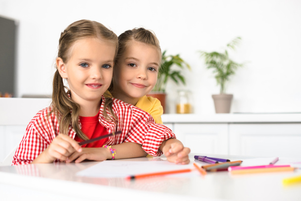 portrait of cute little children at table with papers and pencils for drawing at home - Фото, изображение
