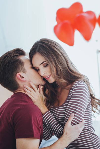 Приємний молодий чоловік цілує свою дівчину
 - Фото, зображення