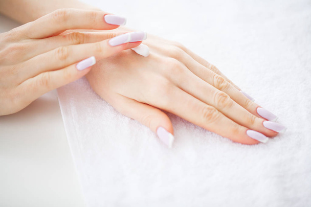 Hand en nagelverzorging. Mooie vrouwen handen met perfecte Manicure toepassing crème op de huid handen. Beauty dag Spa Manicure. - Foto, afbeelding